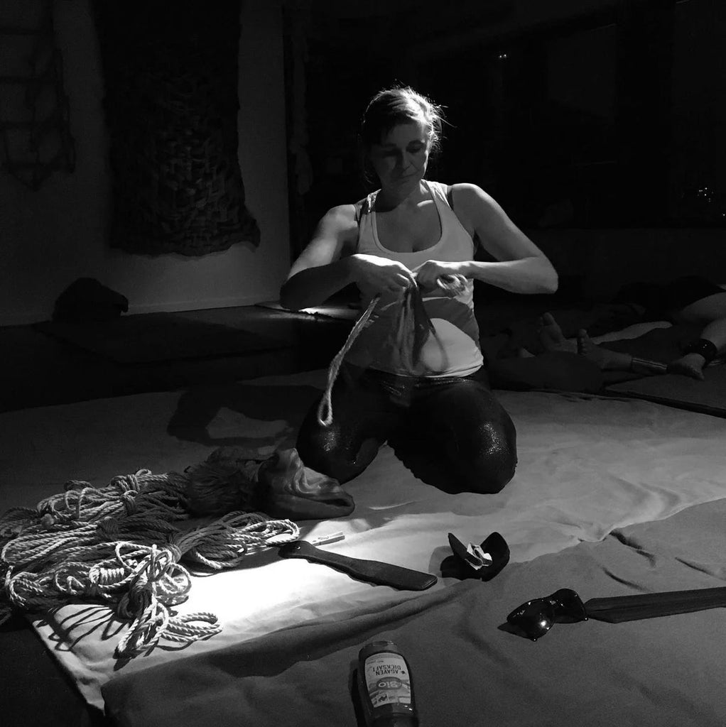 a black and white photo of a woman preparing ropes at a workshop