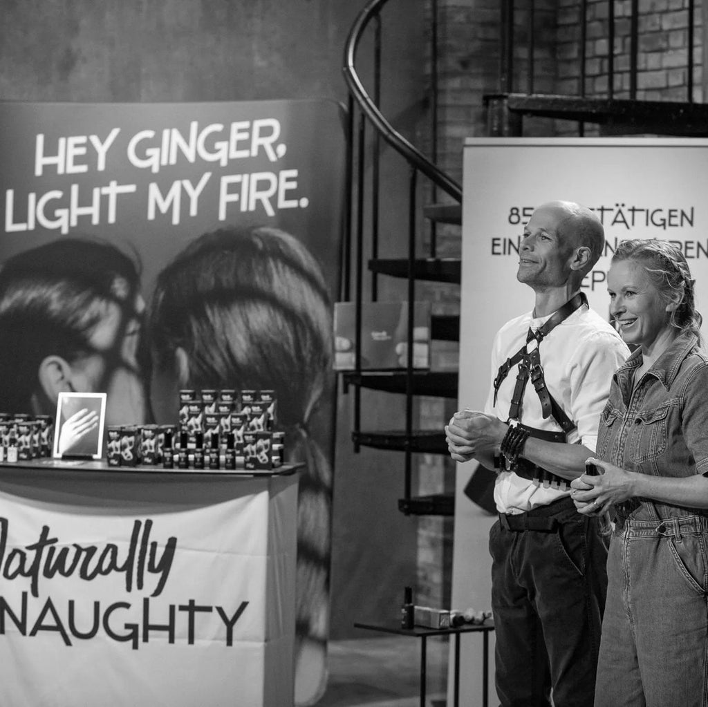 Die beiden Gründer Ina und Ingwer stehen vor ihrem Naturally Naughty Stand und einem Werbebanner mit den Worten "Hey Ginger, light my fire"